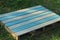 Striped colored wooden table from the pallet lies on the green grass
