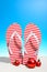 Striped flip-flops and Christmas ornaments on a tropical beach standing on the sand against a Sunny blue sky with copy space