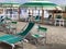 Striped green beach umbrella and sun beds on sandy beach on sunny day. vacation. outdoors furniture