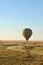 A striped hot air balloon floats above the plains of the Serengeti in Tanzania, Africa at sunrise; vertical image with copy space