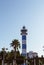 Striped lighthouse next to a palm tree in front of the blue sky