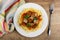 Striped napkin, plate with fried pork meat with lecho and spaghetti, fork on table. Top view