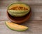 Striped oblong melon in a clay plate and a carved slice on a wooden background