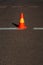 Striped orange cone on the asphalt road.