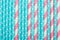 Striped pink and white blue polka dot paper drinking straws laid out as all over pattern backdrop. Kids birthday party celebration