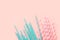 Striped pink and white blue polka dot paper drinking straws on light peachy background. Kids birthday party celebration