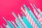 Striped pink and white blue polka dot paper drinking straws on magenta background. Kids birthday party celebration