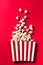 Striped Popcorn Bucket Box on Red Cinemab Background. Movies and Entertainment Concept. Flat Lay