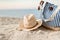 Striped summer bag with straw hat and sunglasses closeup on beach, calm sea background. Sunset time. Copyspace