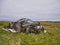 A stripped, rusting, abandoned car on rural farmland on the island of Benbecula in the Outer Hebrides, Scotland, UK