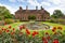 Strode House Barrington Court near Ilminster Somerset England uk with Lily pond garden and red dahlias in summer
