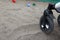 Stroller wheel at sandy beach, closeup. Toys with sand on a blurred background