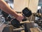 Strong adult man`s hand picking up a dumbbell from organized line of heavy dumbbell equipment in a modern gym for lifting weight