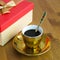 Strong aromatic coffee in a gilded cup with a golden spoon