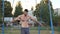 Strong athlete doing cross on gymnastic rings at sports ground. Muscular shirtless sportsman showing hard stunts outdoor