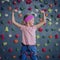 A strong baby climber posing for photographer at artificial wall.