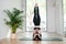 Strong, balanced woman doing unassisted yoga headstand. From behind