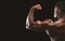 Strong biceps of afro athlete on black background