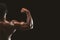 Strong biceps of afro bodybuilder on black background