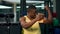 Strong black sportsman talking on a video call on his smartphone while sitting in the gym. Man demonstrates pumped up