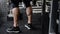 Strong calves of young active athlete male in sneakers standing in sport fitness gym near exercise equipment