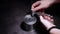 Strong caucasian man with tin-opener opens metal tin can on black table.