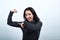 Strong caucasian young woman showing muscles, pointing finger on it