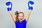 Strong child proud winner boxing competition. Girl child happy winner with boxing gloves posing on grey background. She