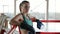 Strong and confident young woman in boxing uniform standing in gym and looking at camera