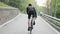 Strong cyclist wearing black outfit riding uphill out of the saddle. Cycling training. Road bike.
