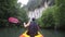 Strong elder man floats kayak to gray cliff