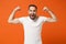 Strong excited young man in casual white t-shirt posing isolated on orange wall background, studio portrait. People