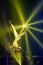 Strong female aerial acrobat make performance upside down on aerial hoop backlit yellow lights.