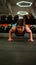 Strong and Fit Athletic Woman in Sport Top and Shorts is Doing Push Up Exercises in a Loft Style Industrial Gym with Motivational