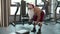 Strong fitness man doing dumbbell swings at gym. Strongman workout in sport club