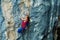 Strong focused woman rock climber making hard move on challenging route on cliff