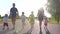 A strong friendly family holding hands runs along the road at sunset.