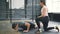 Strong guy doing push-ups in crossfit gym while trainer young woman speaking motivating student