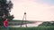 Strong guy walking, a beautiful green tree, grass, against the background of the Dnieper River, bridge, along the path