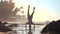Strong gymnast silhouette balances on head on wet sand
