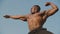 Strong handsome african american bodybuilder showing his perfect muscles on the clear blue sky background