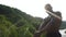 Strong handsome african american bodybuilder is training on the rock in mountains. Green forest mountain background