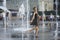 Strong heat in the city: laughing little girl playing with fountain water jets at the square. June 5, 2018. Kiev, Ukraine