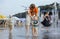 Strong heat in the city: man and little boy playing with fountain water jets at the square