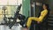 Strong hispanic brunette sportswoman doing legs exercise on sport simulator in fitness club. In yellow sportswear