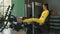 Strong hispanic brunette sportswoman doing legs exercise on sport simulator in fitness club. In yellow sportswear