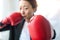 Strong and independent businesswoman in a business suit and boxing gloves looking menacingly at the camera.