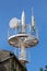 Strong large white metal stand for multiple antennas and cell phone transmitters on top of old dilapidated building with clear