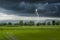 Strong lightning in black clouds over green field