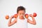 Strong little caucasian kid in white tank top lifting dumbbells of apple during training sport workout with mind concentration